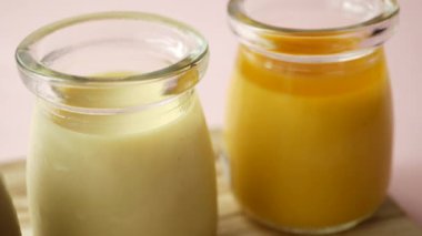  Karamel, çikolata ve mango pudingi pembe arka planda cam bir kavanozda. ,