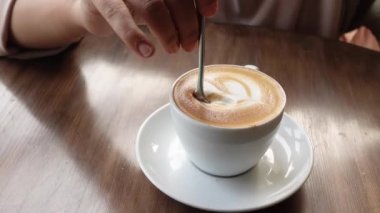 İnsan, kaşıkla kahve karıştırır.