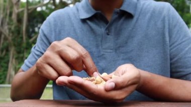 young men eating mux nut sitting on park .