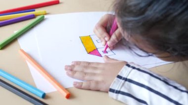  side view of little girl at her table drawing.,