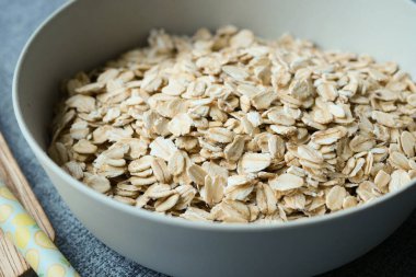 Close up of roasted oats flakes in a bowl on table .