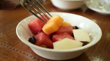 eating mixed fruit in a bowl on table ,