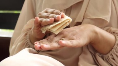 women n disinfecting his hands with a wet wipe..