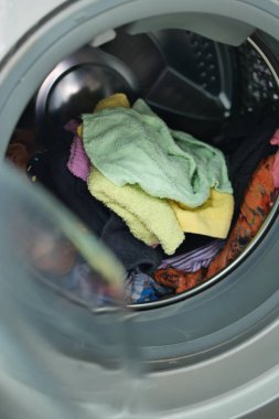 Adam çamaşır makinesine gömlek koyuyor.