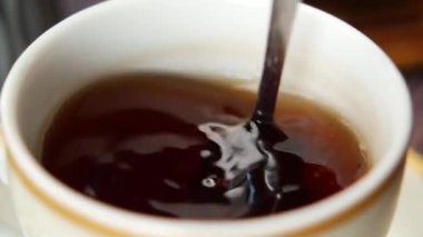 İnsan, kaşıkla kahve karıştırır.