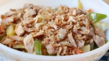 spoon pick tuna salad from a bowl on table .