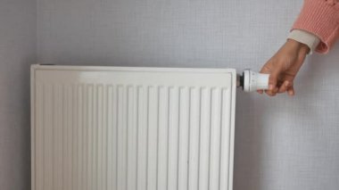women hand changing temperature on heating radiator .