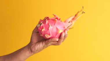  men holding a dragon fruit against yellow background .