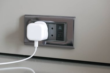  white color power cord cable plugged into wall .