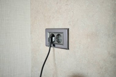  white color power cord cable plugged into wall .