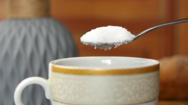 Çay bardağına beyaz şeker dökmenin yavaş çekimi .