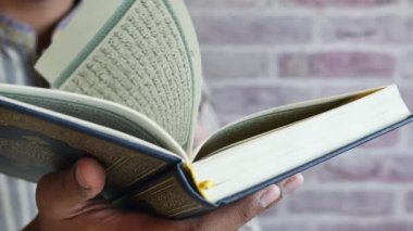 Müslüman adam Kuran-ı Kerim 'i elinde tutuyor. ,