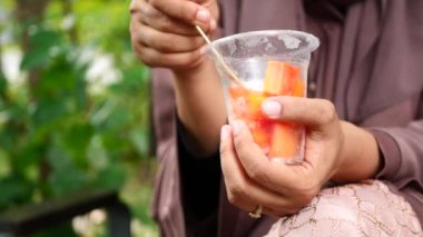 Kadınlar plastik bir kabın içinden papaya yiyorlar. .