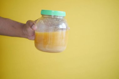 homemade ghee in container against yellow background .