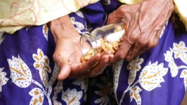 senior women eating pouring peanuts on hand ,