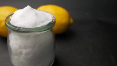 salt in a jar and lemon on black background .