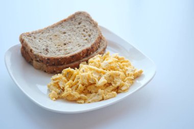 Scrambled eggs on a bread on white plate 