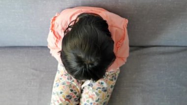 a upset child girl cover her face with hand .