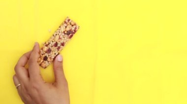 holding a oat protein bar on yellow background .