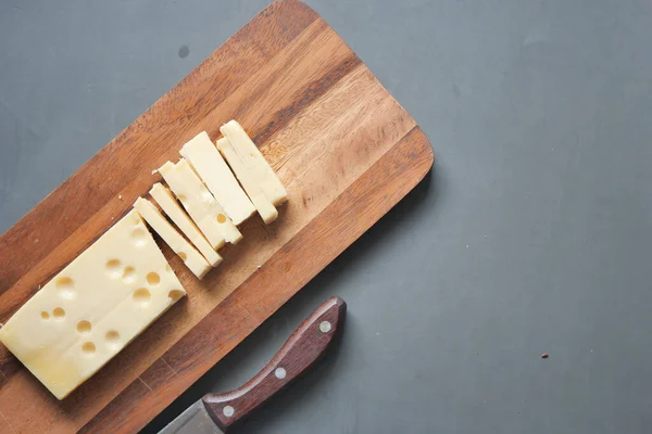 Stock image sliced cheese with holes on a chopping board on table .