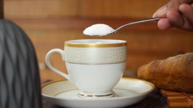 Kahve bardağına beyaz şekerin yavaş yavaş dökülmesi, üst manzara. ,