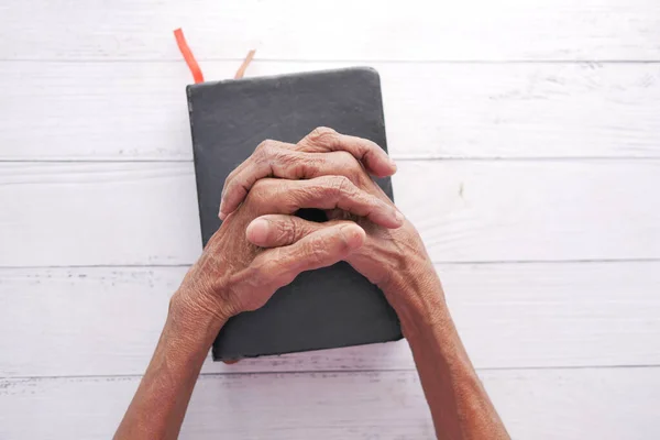 上了年纪的女人手里拿着圣经在他手里祈祷 — 图库照片