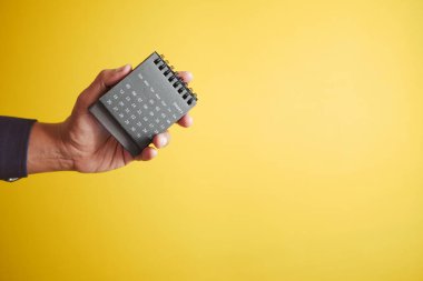  Sarı arkaplana karşı bir takvim tutuyor .