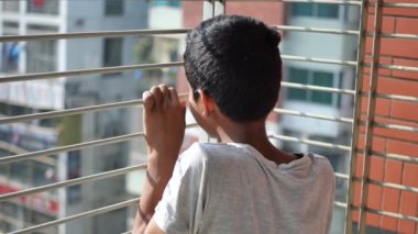 sad teenage boy looking through window .