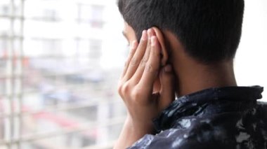 teenage boy having ear pain touching his painful ear 
