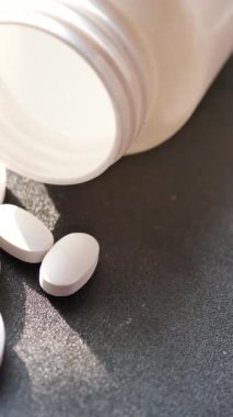  Siyah arka plana beyaz renkli tıbbi haplar dökülüyor. .