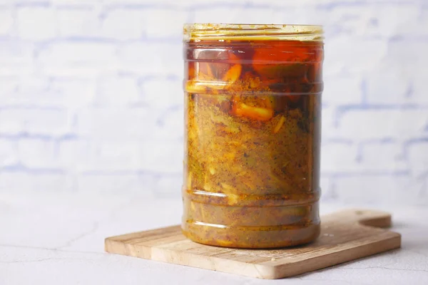 Homemade Mango Pickle in a glass jar on table