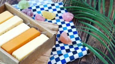 Cheese cubes green, yellow and red color on chopping board .