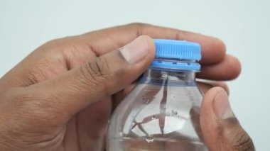 Plastik bir su şişesinin kapağını aç. .
