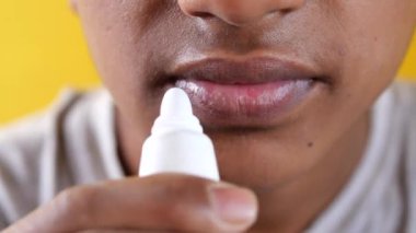  Genç adam dudaklarına nemlendirici dudak kremi sürüyor..