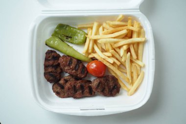 Yemek paketinde patates kızartması ve kebap. .