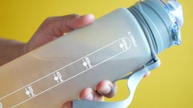 Elinde bir su şişesi vardı. Yakından. ,