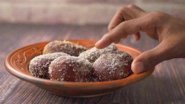  Masadaki bir kasedeki Hint tatlısını elle seç.