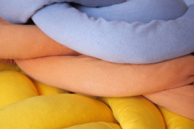Bir yığın turuncu, gri ve sarı renkli yastık 