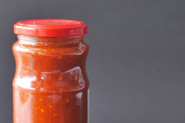 chili tomato sauce in a small jar on table 
