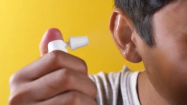 Close up of men using spray to remove earwax.