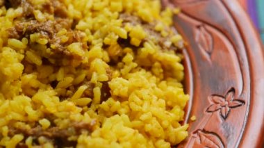 boiled yellow rice with meats on a plate .