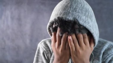 Kapüşonlu üzgün adam elleri siyah kaplı.