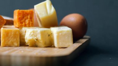 Cheese cubes green, yellow and red color on chopping board .