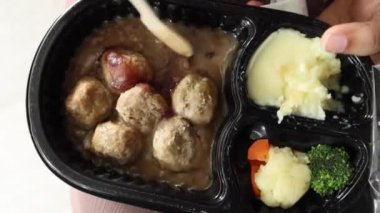 curry chicken and rice in a take away plastic packet on table .