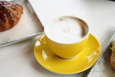 Masanın üzerinde sarı bir fincanda sıcak kahve. .