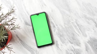 Mermer taşlı arka planda yeşil ekranlı akıllı telefon