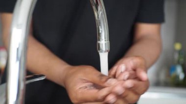 Genç adam ellerini sıcak suyla yıkıyor. ,