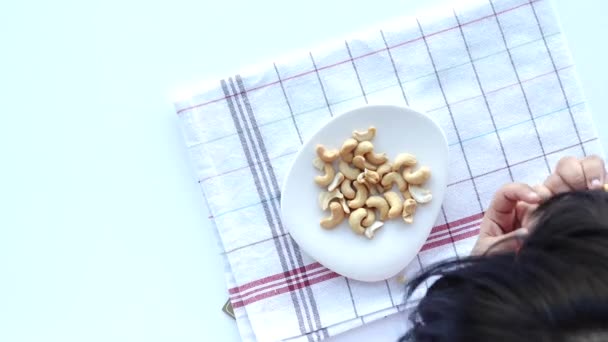 小孩用手在桌上的碗里挑食花生 — 图库视频影像