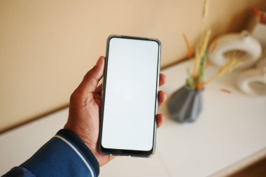  Ev arka planında boş ekranlı cep telefonu tutan eller .