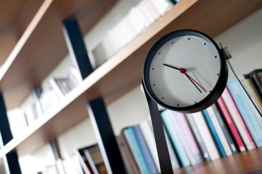 simple modern clock on a book shelf